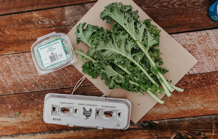 a bunch of romaine lettuce, a dozen eggs and sprouts on a table 